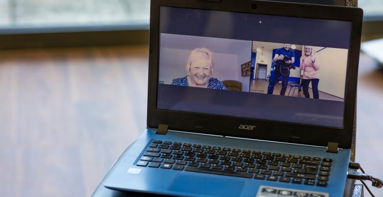 A screen showing an older woman watching a virtual exercise class.
