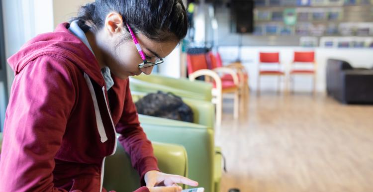 Young teenage girl sitting down looking at her phone