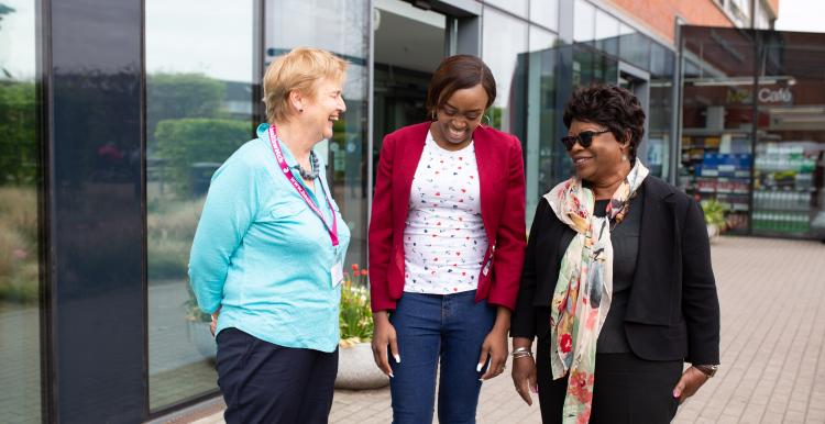 Three woman standing outside a hospital laughing and talking