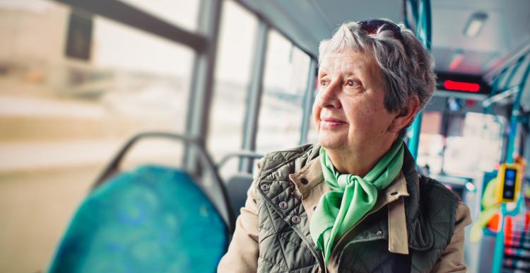 Picture of older woman sitting on a bus looking out the window