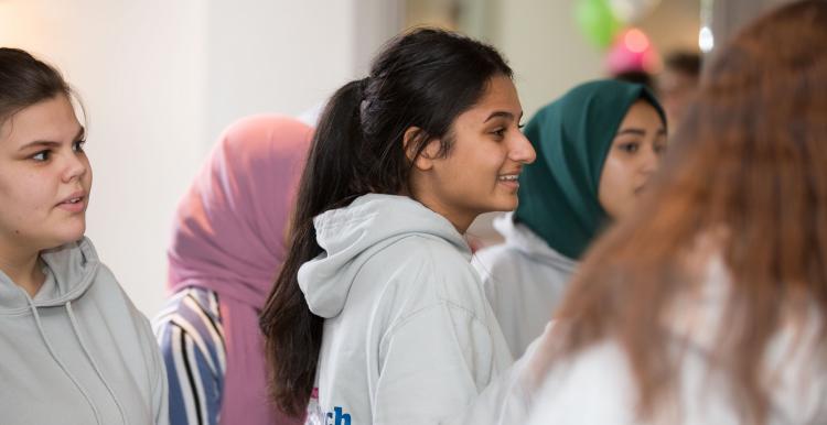 A group of teenagers standing and talking and smiling