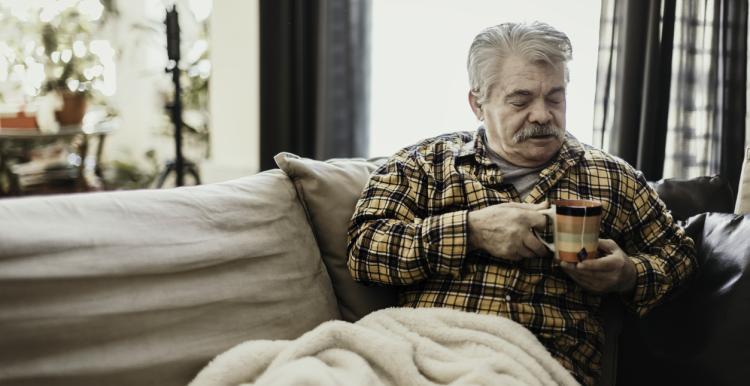 man on sofa holding a mug