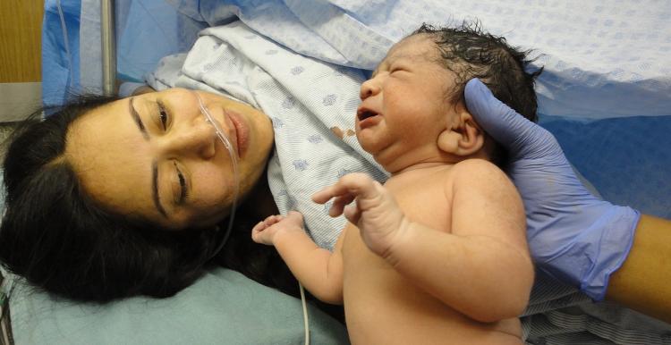 Woman who has just given birth looking at her newborn baby