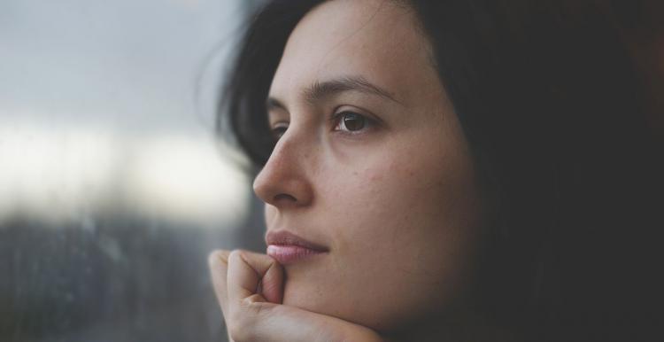 woman looking out a window thinking 