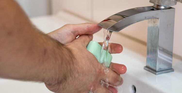 Information on Coronavirus Close up of man washing hands with a bar of soap in a white sink and a silver tap