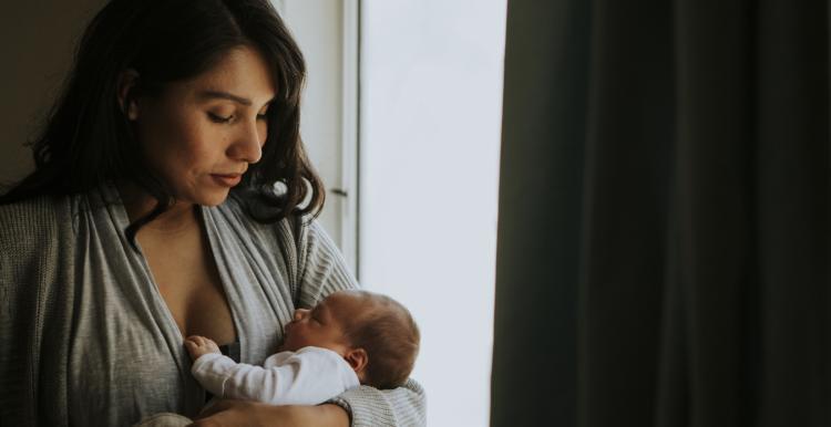 women holding baby near a window