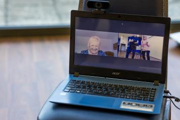 A screen showing an older woman watching a virtual exercise class.