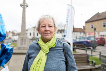 Older woman from the public wearing a green camera looking front on to the camera