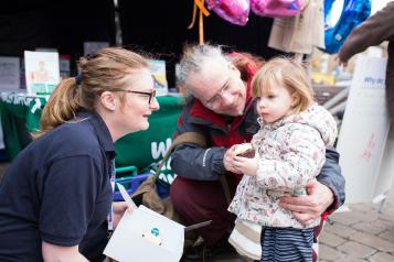 Healthwatch staff member talking to a young child at an event