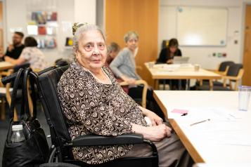 Elderly woman at an engagement event in a wheelchair looking directly at the camera