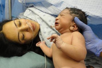 Woman who has just given birth looking at her newborn baby