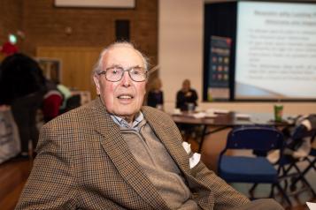 Older man at an event looking at the camera