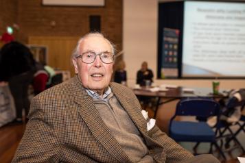 Older man at an event looking at the camera 