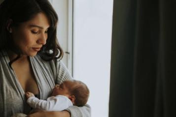women holding baby near a window